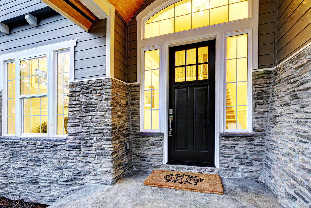 A beautful home with a traditional black front door with left and right sidelites and a transom.