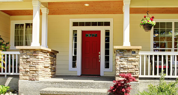 A modern, red steel entry door on home with two replacement windows.