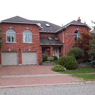 red brick house with double garage doors and two semi-circle windows