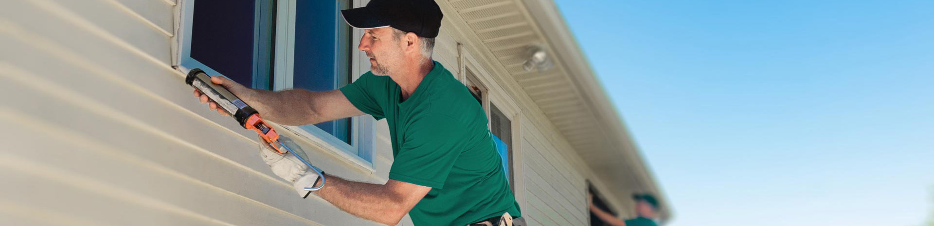 A window installer putting caulking on the exterior of a window.