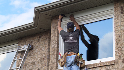 An installer on a ladder installing a new window.