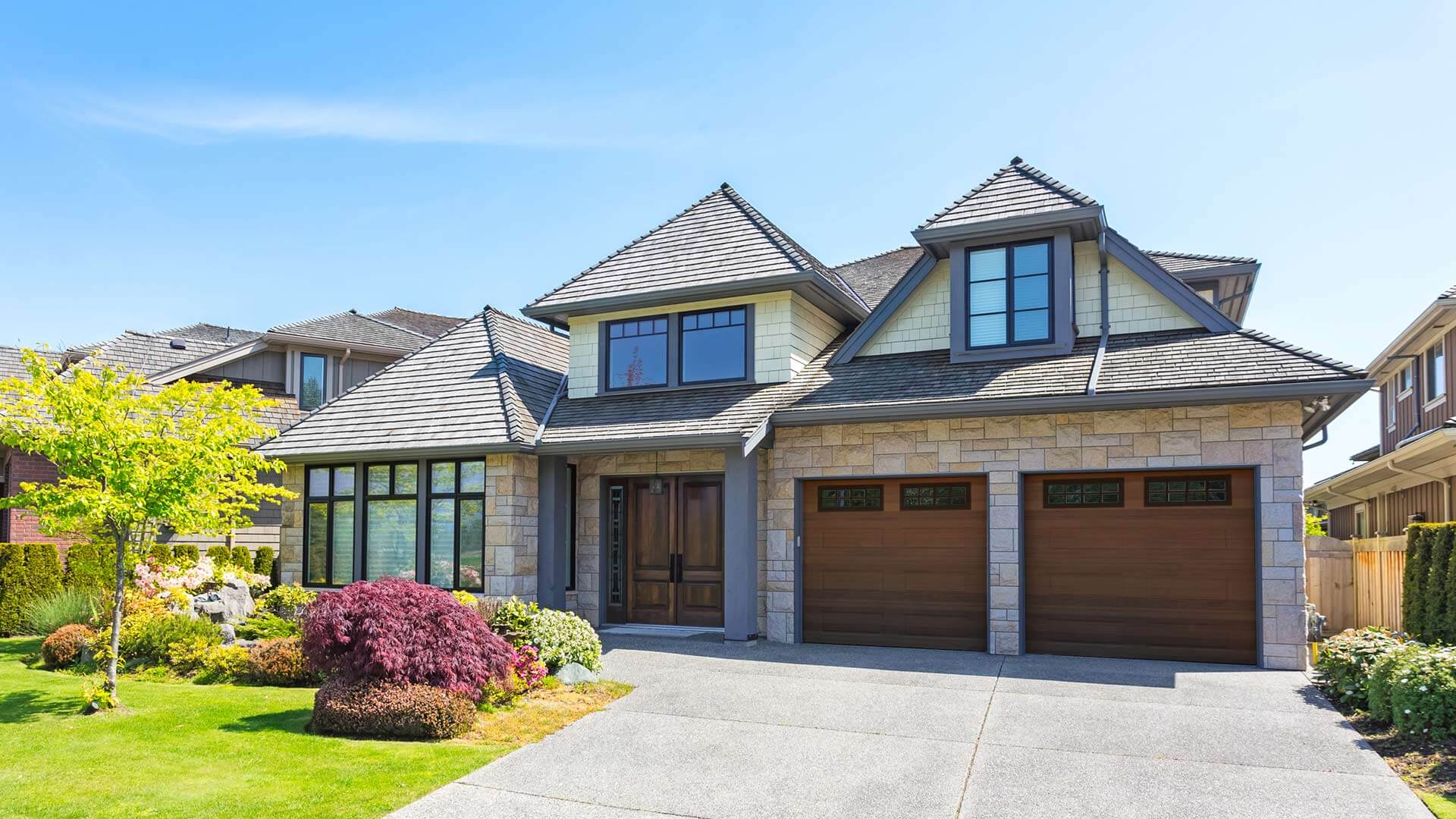 Modern suburban detached house featuring a double garage with black framed windows  . 