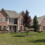 upscale brick home with tan accents over windows