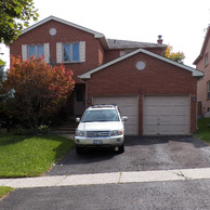 brick home with white shutters and garage doors