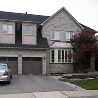 stone house with bay window and carriage style garage doors