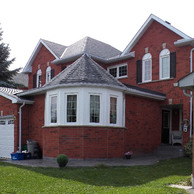 red brick home with black shutters and bow windows