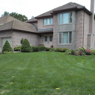 tan brick house with two garage doors and side bay window