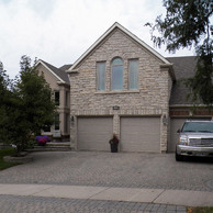 tan stone house with three car grage