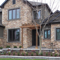 stone home with pergola over front door close up view