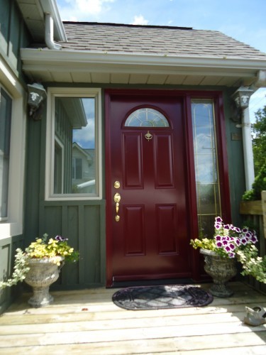 dark red steel door on green house